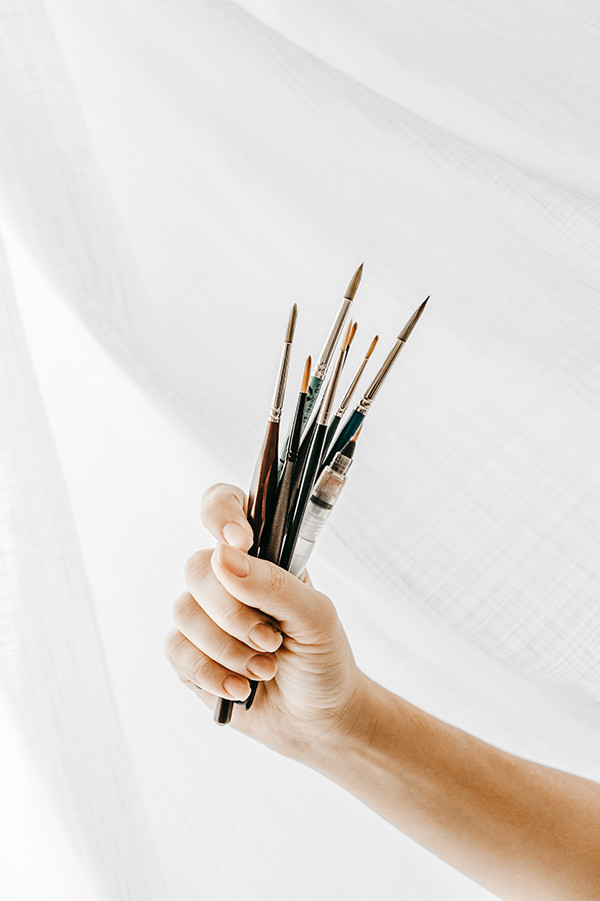 Hand with brushes in front of a white wall